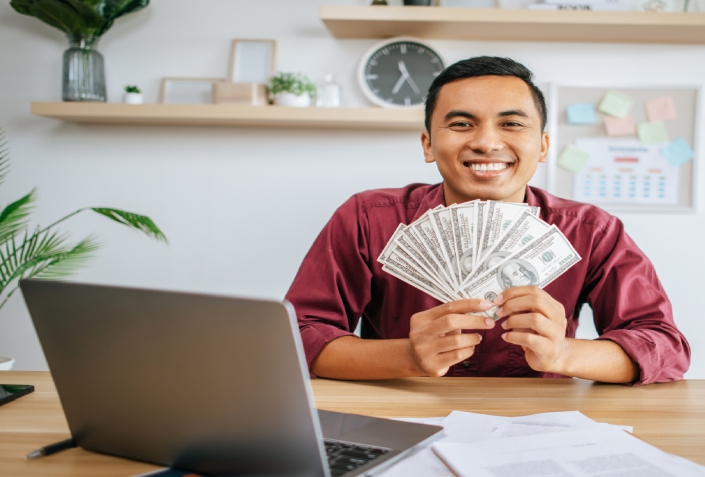 a man working in an office and holding money.
